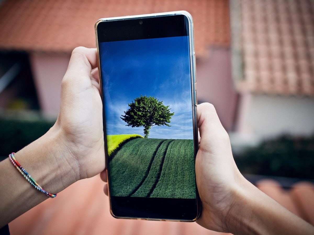 乐播投屏 App 在手机上打开后显示附近可连接电视的界面，客厅暖光下手机与电视并排放置